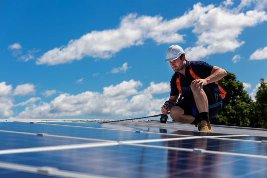 A solar panel installer observes the angle of solar panels installed on a roof