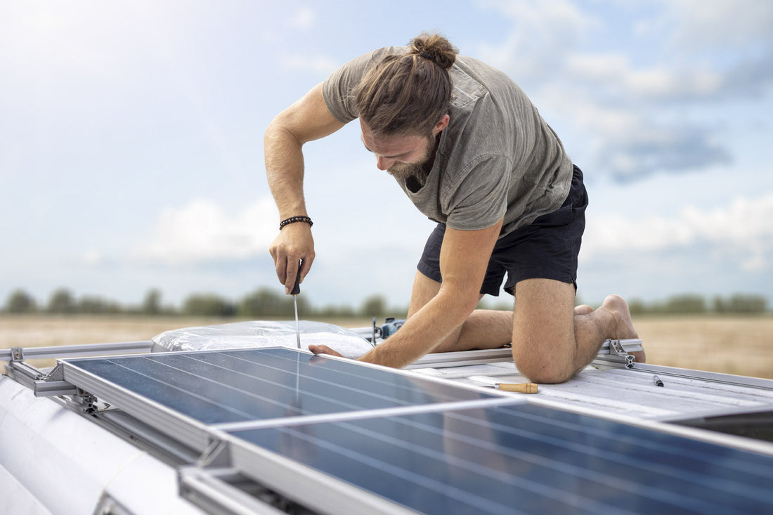 An outdoorsy DIYer uses a screwdriver to connect solar panels to their RV