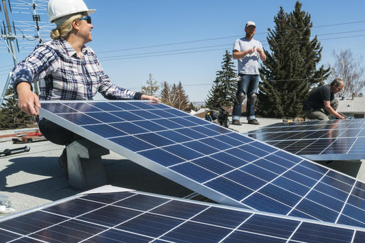 Three solar panel installers chat as they install rooftop solar panels