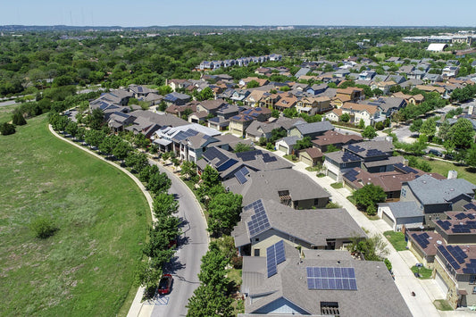 An elevated view of a suburban neighborhood showing solar panels on most of the houses