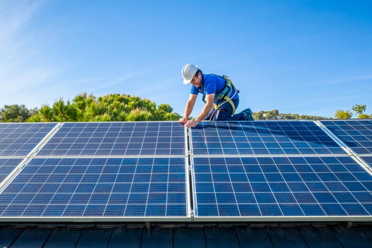 A solar leasing company’s installer wears a white hard hat and a blue shirt while installing rooftop solar panels