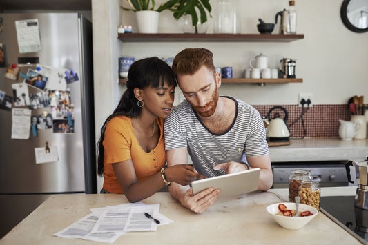 A couple sits at their kitchen table and uses a tablet to determine the cost of their solar panels