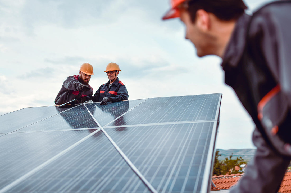 Three solar panel installers use a tape measure to determine solar panel size