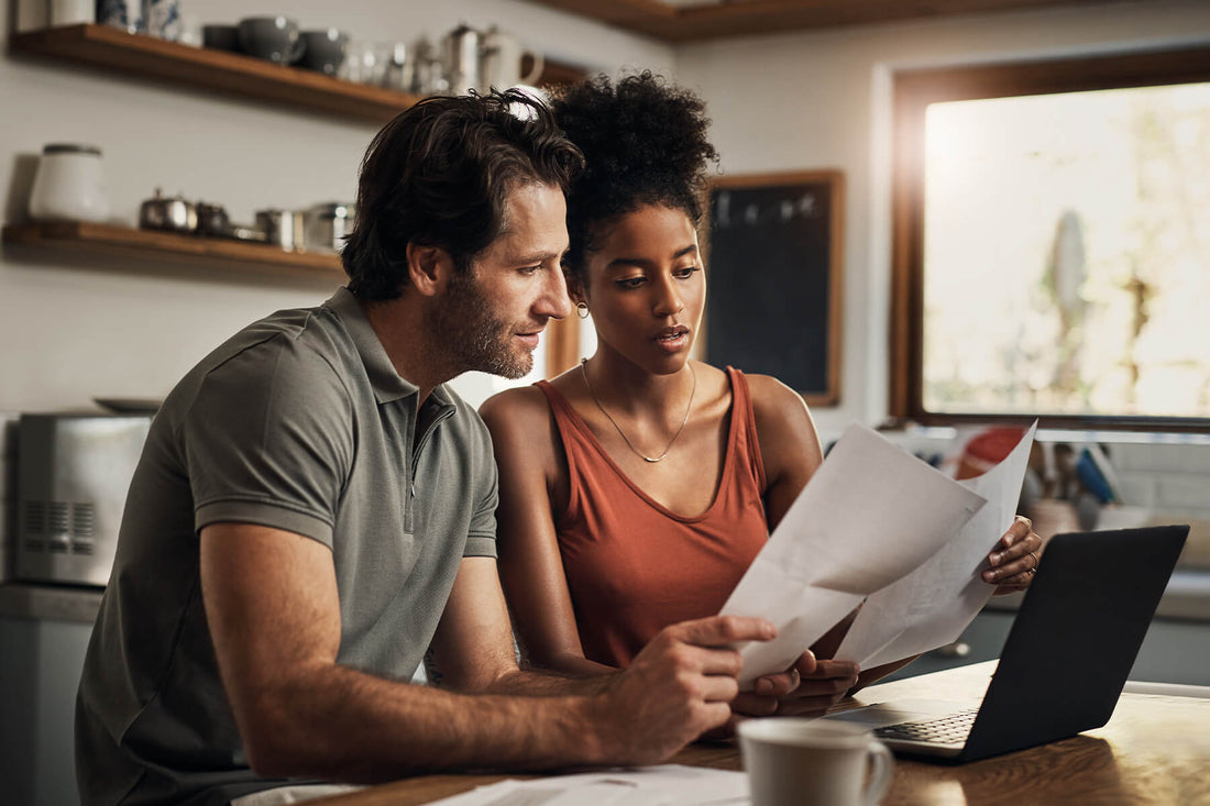 A couple holds papers in front of a table with a laptop to discuss the cost of solar panels